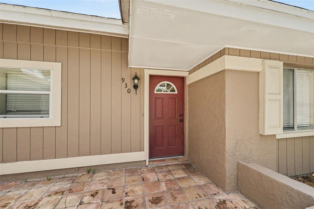 The exterior of a house features a red front door, tan siding, and a tiled porch — 930 OAK FOREST DRIVE, WINTER SPRINGS, FL