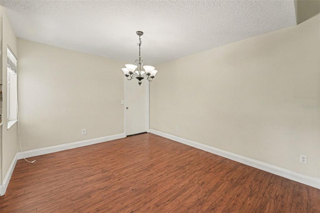 An empty dining room features wood-look flooring, beige walls, and a traditional chandelier — 930 OAK FOREST DRIVE, WINTER SPRINGS, FL