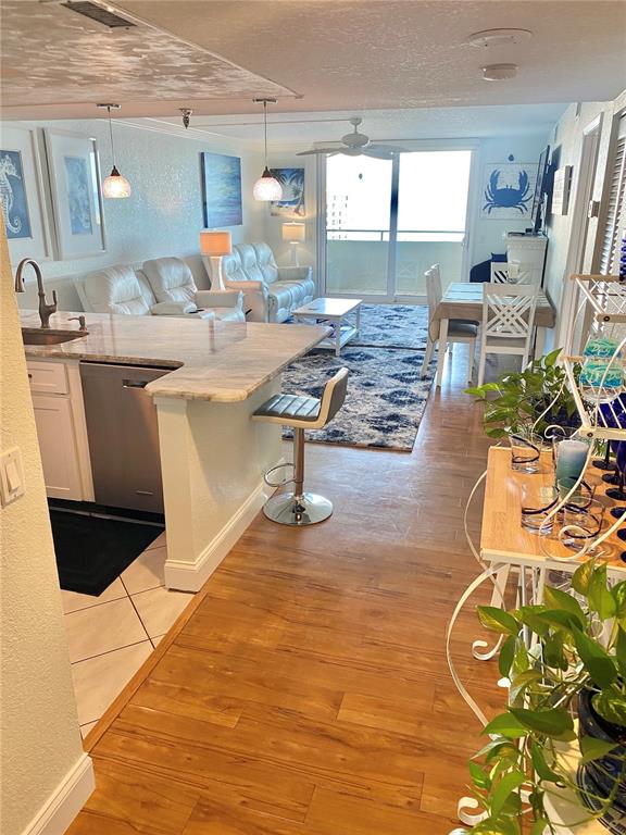 An open-concept kitchen and living area features a breakfast bar, tile flooring, and balcony access — 6035 SEA RANCH DRIVE UNIT 901, HUDSON, FL