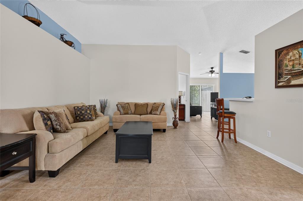 A living room features beige sofas, a black coffee table, and tile flooring — 4338 STONEFIELD DRIVE, ORLANDO, FL