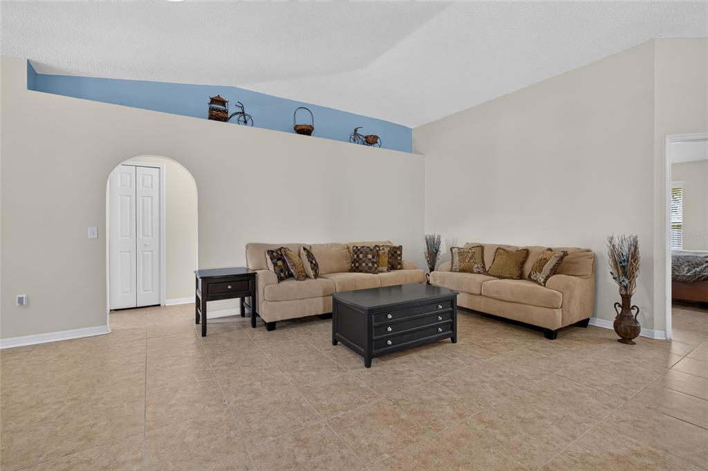 A living room features beige sofas, a black coffee table, and a blue display ledge — 4338 STONEFIELD DRIVE, ORLANDO, FL