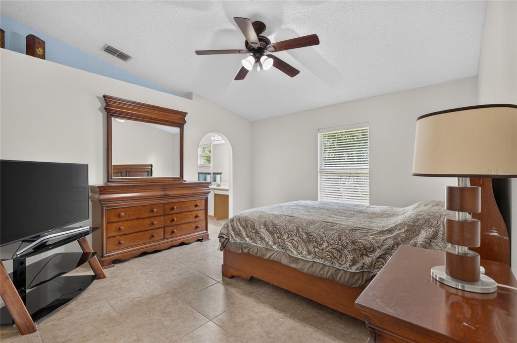 A bedroom features a wooden bed frame, a matching dresser with a mirror, and tile flooring — 4338 STONEFIELD DRIVE, ORLANDO, FL