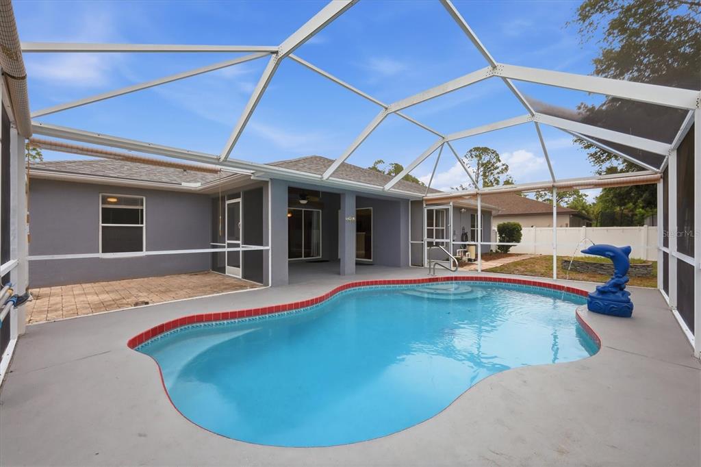 A backyard swimming pool with a dolphin fountain inside a white screened-in lanai enclosure — 3575 LUBEC AVENUE, NORTH PORT, FL