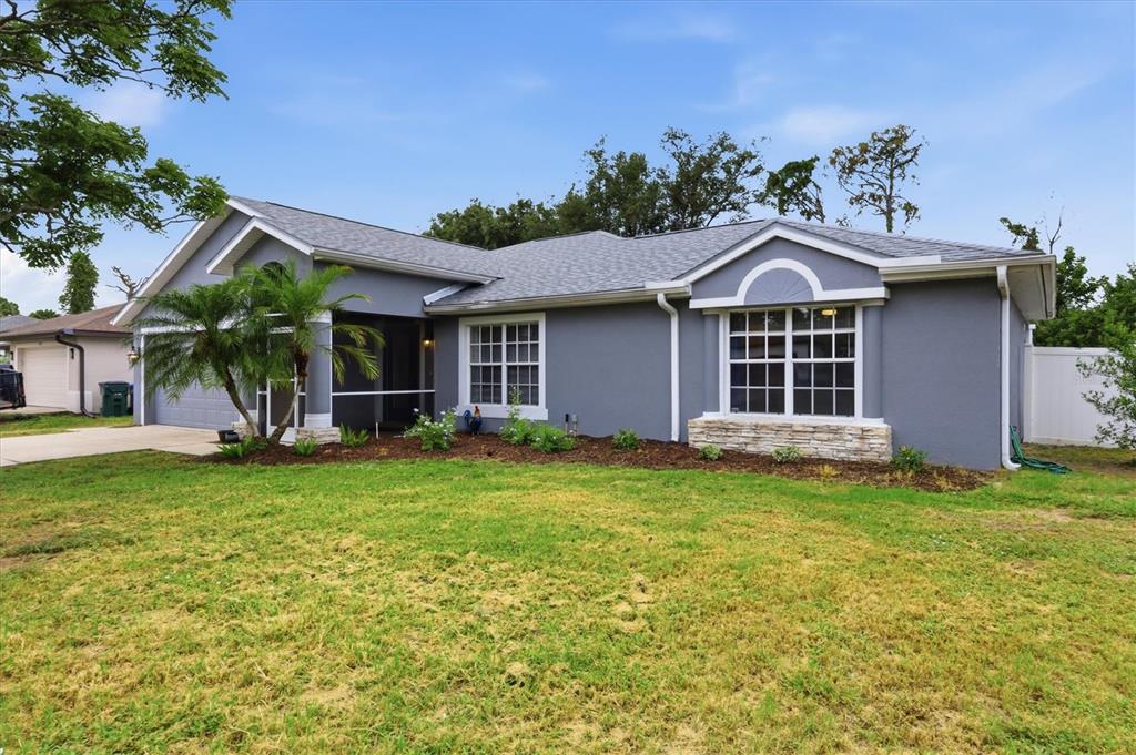 A gray single-story house with a front-facing gable, stone accents, and a grassy lawn — 3575 LUBEC AVENUE, NORTH PORT, FL