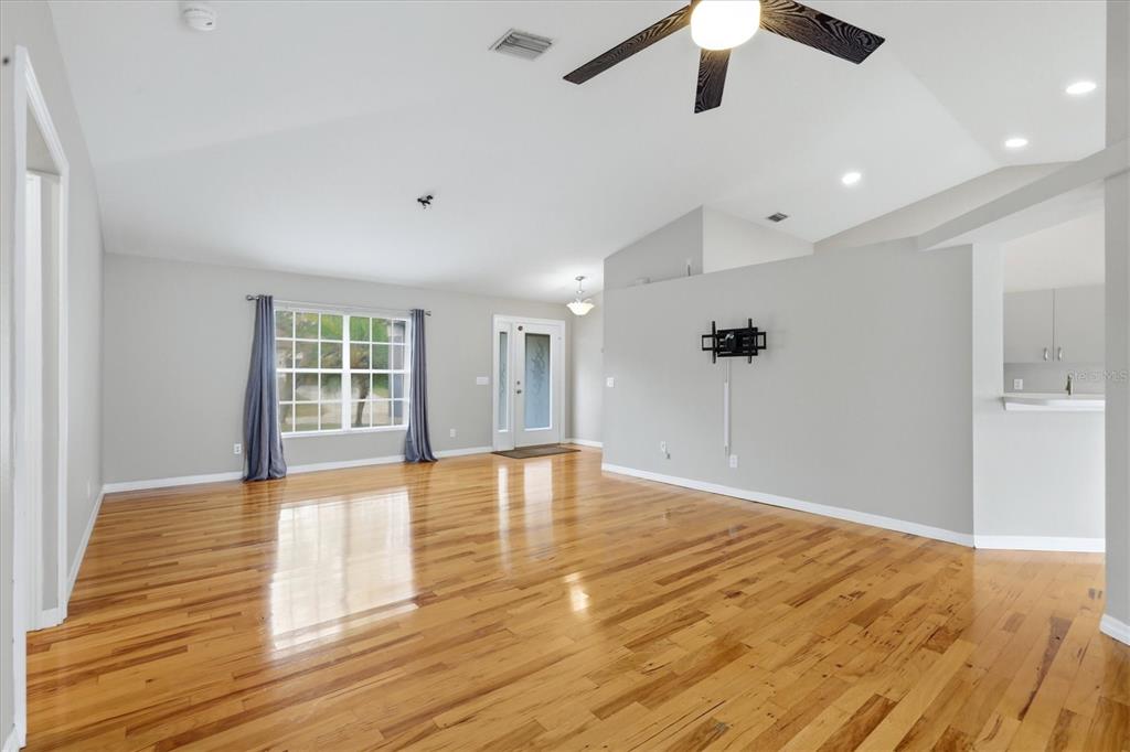 A spacious living room features hardwood floors, a vaulted ceiling, and a ceiling fan — 3575 LUBEC AVENUE, NORTH PORT, FL