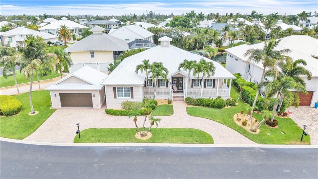 An aerial view of a single-story house with a white metal roof and paved driveway — 6050 TIDEWATER ISLAND CIRCLE, FORT MYERS, FL