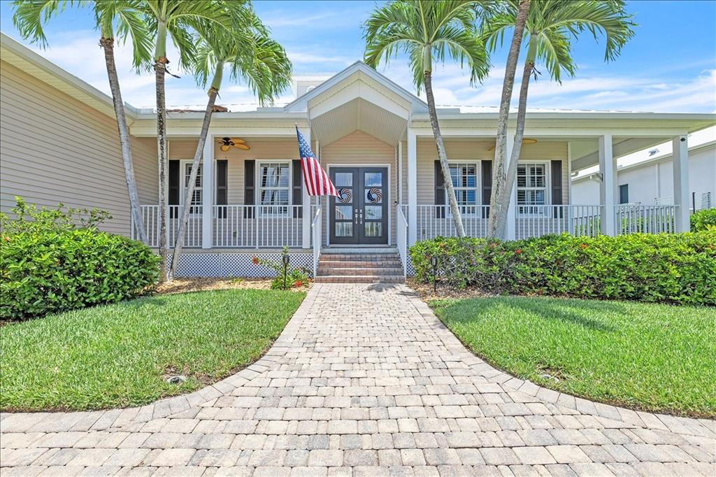 A paved walkway leads to the front entrance of a house with palm trees — 6050 TIDEWATER ISLAND CIRCLE, FORT MYERS, FL