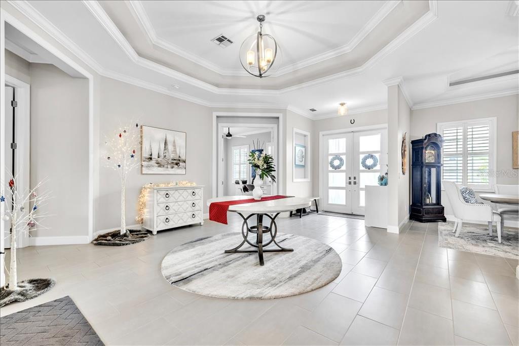 A bright, tiled foyer features a tray ceiling, a round table, and a grandfather clock — 6050 TIDEWATER ISLAND CIRCLE, FORT MYERS, FL