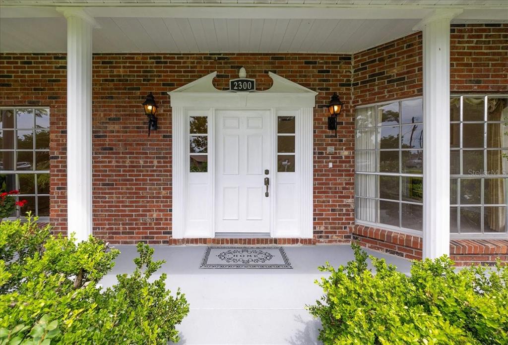 The front entrance of a brick house features a white door with sidelights and columns — 2300 SE 38TH COURT, OCALA, FL