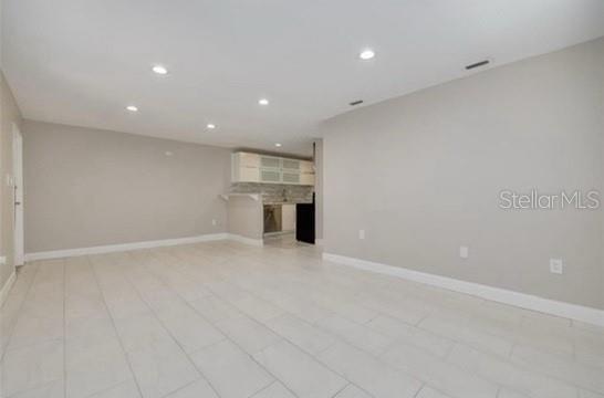 An open-concept living area features light-colored tile flooring, recessed lighting, and a kitchen in back — 334 48TH AVENUE N UNIT 236, ST PETERSBURG, FL