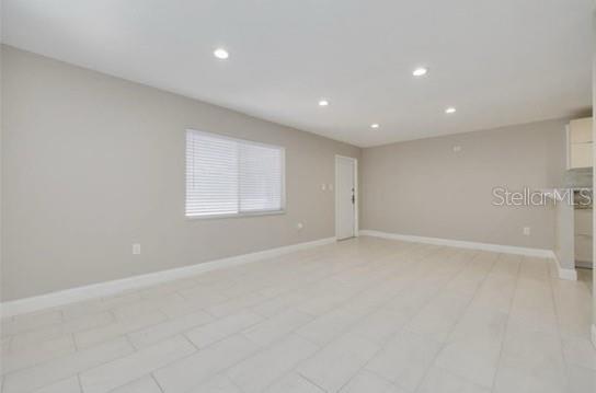 A bright, empty room features light-colored tile flooring, neutral walls, and a large window — 334 48TH AVENUE N UNIT 236, ST PETERSBURG, FL