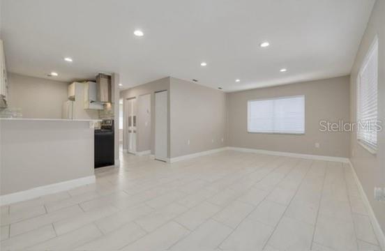A bright, open-concept living area features light-colored tile flooring and a kitchen with white cabinets — 334 48TH AVENUE N UNIT 236, ST PETERSBURG, FL