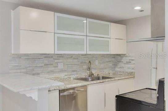 A kitchen features white cabinets, a granite countertop, a stainless steel sink, and tiled backsplash — 334 48TH AVENUE N UNIT 236, ST PETERSBURG, FL