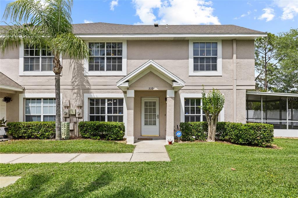A two-story tan stucco townhouse with a front entrance, white trim, and a manicured lawn — 539 KENSINGTON LAKE CIRCLE, BRANDON, FL