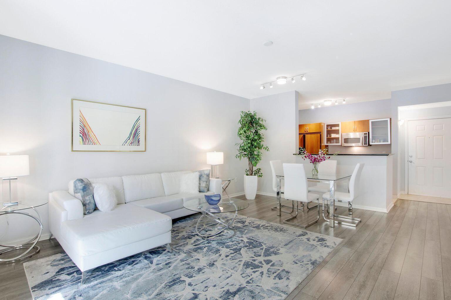 A living room with a white sectional sofa, glass coffee table, and adjacent dining area — 802 W Windward Way # 206, Lantana FL 33462, LANTANA, FL