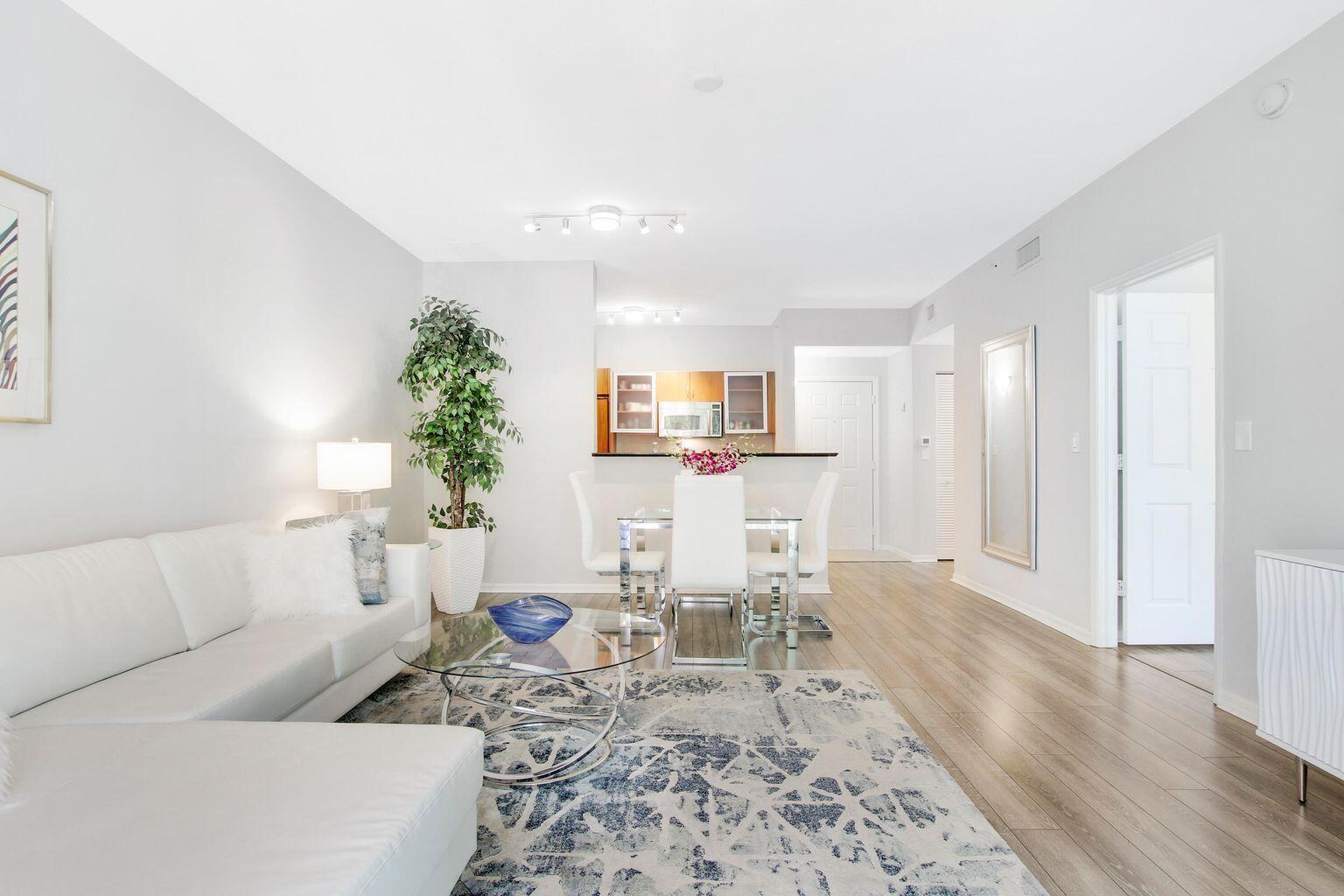 A living room with a white sectional sofa, glass coffee table, and dining area — 802 W Windward Way # 206, Lantana FL 33462, LANTANA, FL