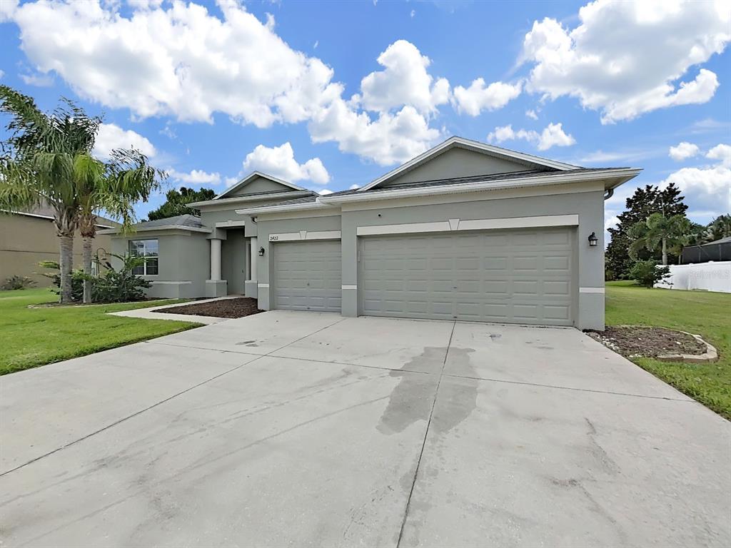 A single-story house with a three-car garage and a concrete driveway under a cloudy sky — 2422 ALLEGHENY VALLEY STREET, RUSKIN, FL