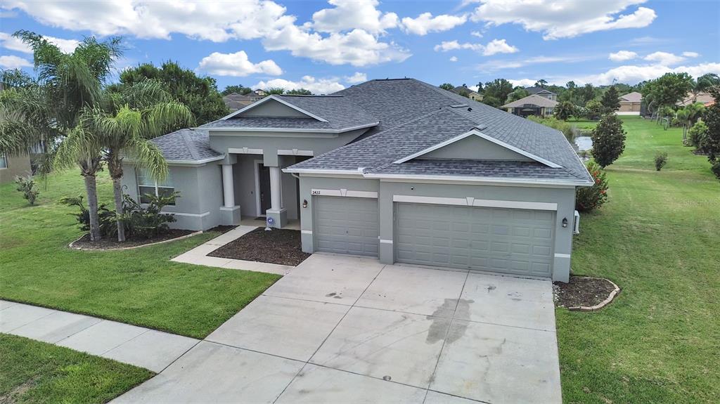 An aerial view shows a gray single-story house with a three-car garage and palm trees — 2422 ALLEGHENY VALLEY STREET, RUSKIN, FL