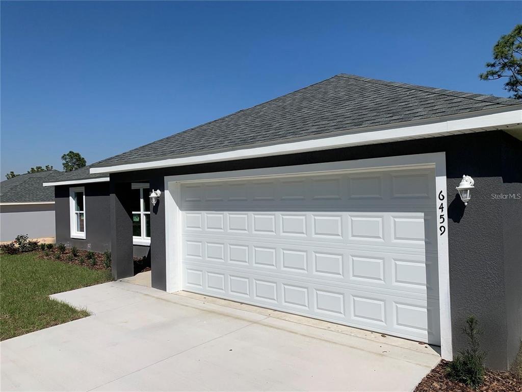 A view of a dark gray house exterior featuring a white two-car garage door — 6459 SW 204TH AVENUE, DUNNELLON, FL