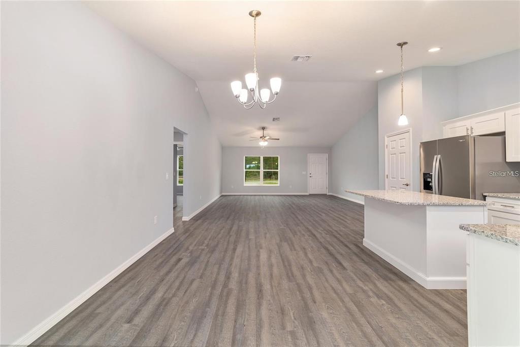An open-concept living area features light blue walls, wood-look flooring, and a kitchen island — 6459 SW 204TH AVENUE, DUNNELLON, FL