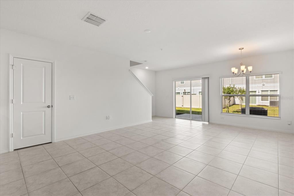 An empty room with white walls, tiled floors, a sliding glass door, and a chandelier — 2330 CARRABELLE WAY, SANFORD, FL