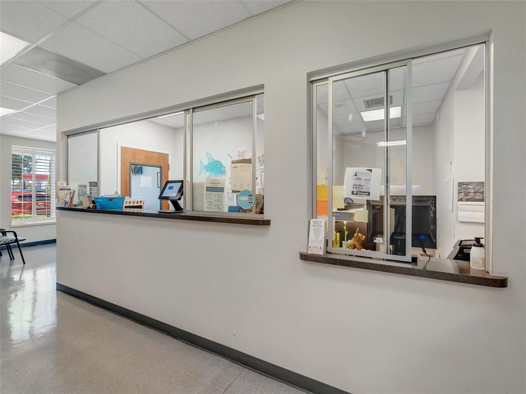 A reception area features two sliding glass windows with counters and white walls — 11183 S ORANGE BLOSSOM TRAIL UNIT 103 / 102, ORLANDO, FL