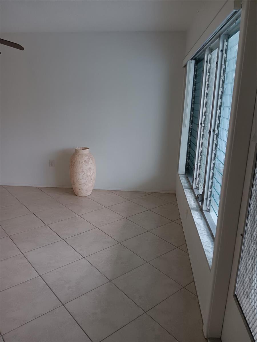 A room with beige tile flooring, white walls, and a large textured vase near windows — 1110 N Riverside Drive # 26, Pompano Beach FL 33062, POMPANO BEACH, FL