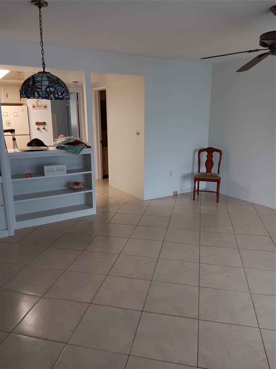 An open-concept dining area features light-colored tile flooring, a built-in shelving unit, and a pendant light — 1110 N Riverside Drive # 26, Pompano Beach FL 33062, POMPANO BEACH, FL