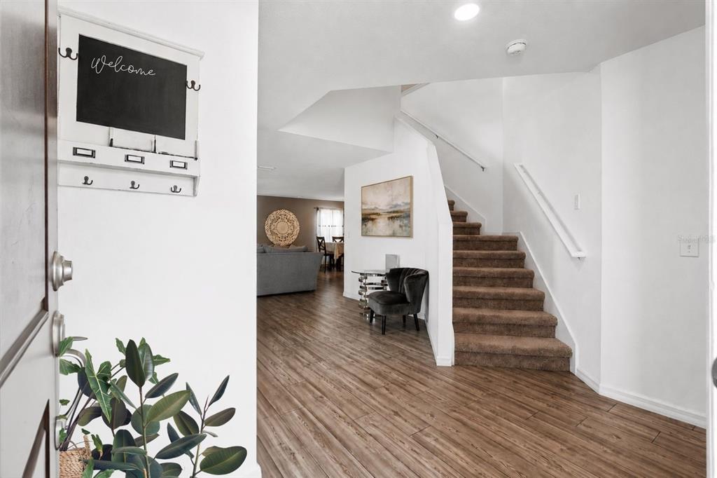 An entryway features wood-look flooring, a staircase with brown carpet, and a wall-mounted chalkboard — 8567 INDIAN LAUREL LANE, BROOKSVILLE, FL