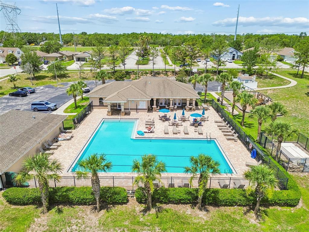 An aerial view of a community clubhouse with a swimming pool, patio, and palm trees — 8567 INDIAN LAUREL LANE, BROOKSVILLE, FL