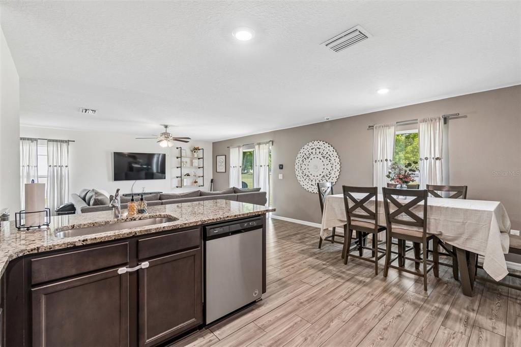 An open-concept kitchen with granite countertops overlooks a dining area and living room — 8567 INDIAN LAUREL LANE, BROOKSVILLE, FL