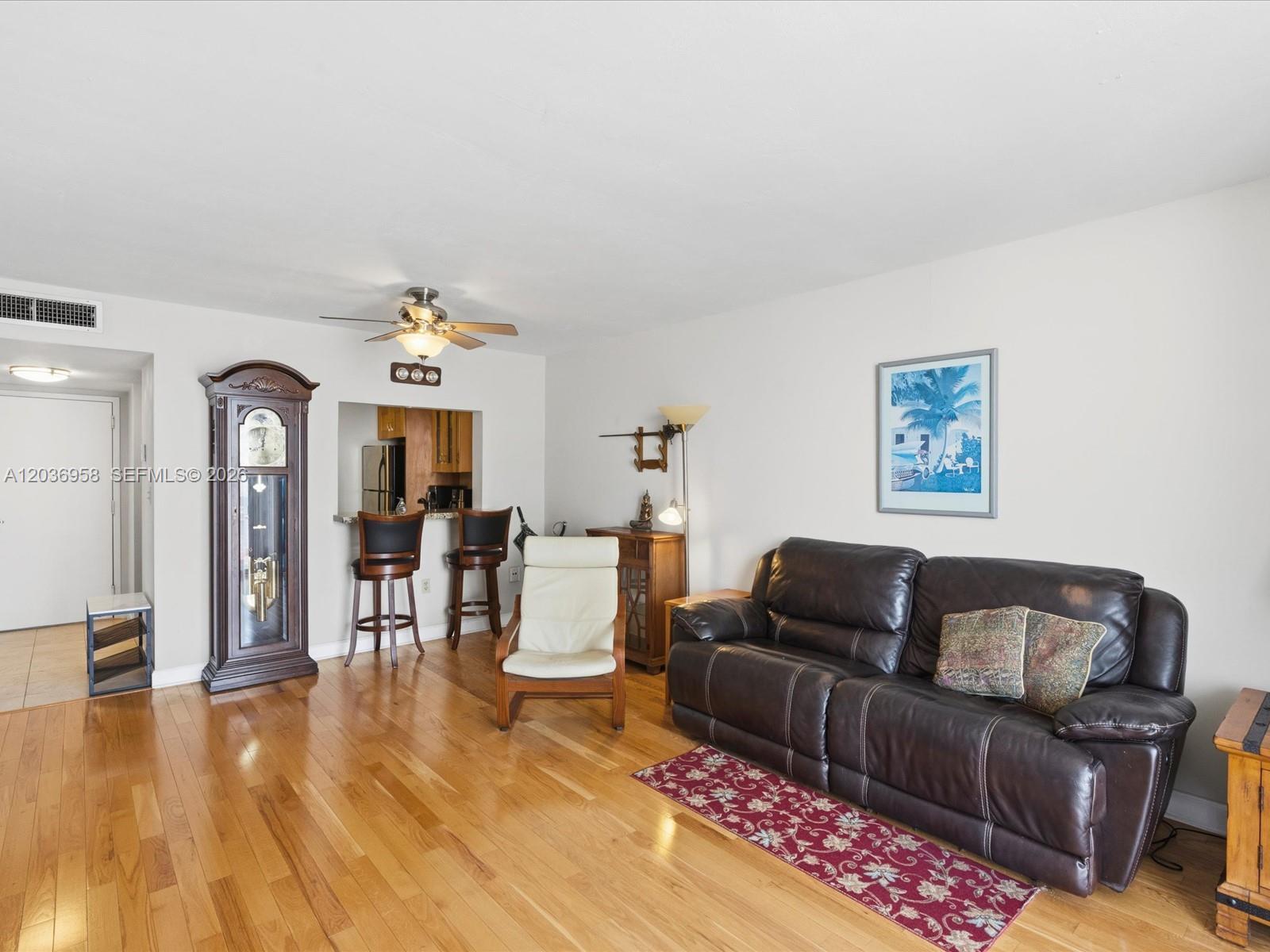 A living room features hardwood floors, a dark leather sofa, and a grandfather clock — 3588 Collins Ave # 504, Miami Beach FL 33140, MIAMI BEACH, FL
