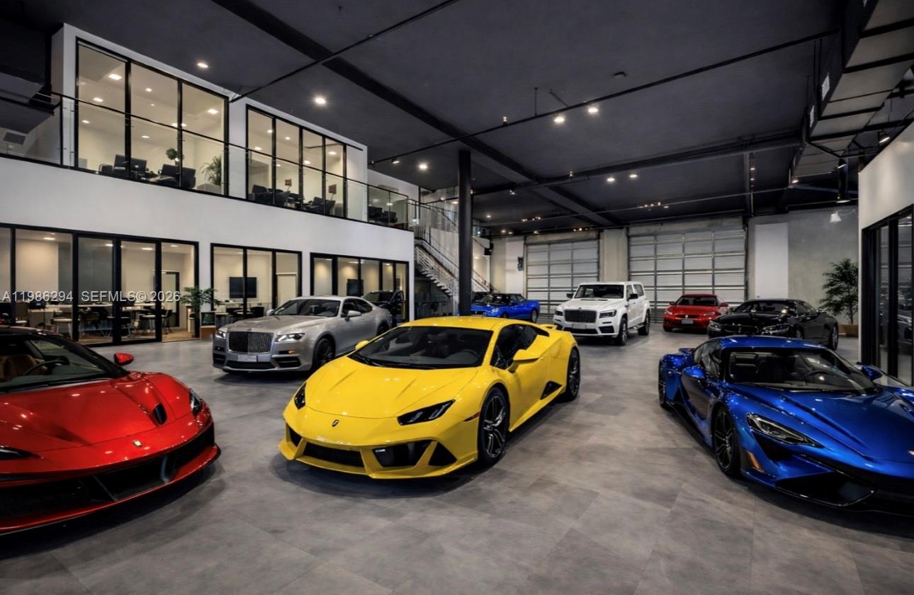 A spacious, modern indoor showroom features a polished concrete floor and several luxury sports cars — 2950 N 28th Ter, Hollywood FL 33020, HOLLYWOOD, FL
