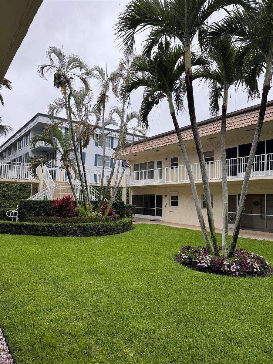 A grassy courtyard with palm trees sits between two multi-story apartment buildings — 632 Snug Harbor Drive # D6, Boynton Beach FL 33435, BOYNTON BEACH, FL