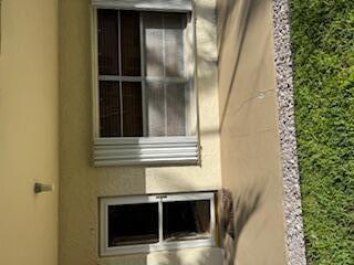 A beige exterior wall features a glass storm door and a window with accordion shutters — 632 Snug Harbor Drive # D6, Boynton Beach FL 33435, BOYNTON BEACH, FL