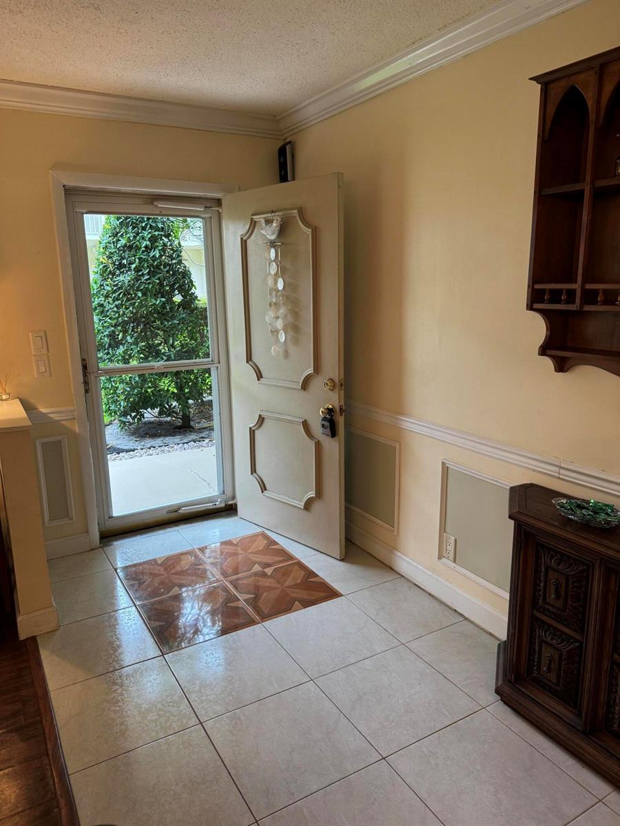 A tiled entryway features a light-colored door, a storm door, and a wooden wall shelf — 632 Snug Harbor Drive # D6, Boynton Beach FL 33435, BOYNTON BEACH, FL