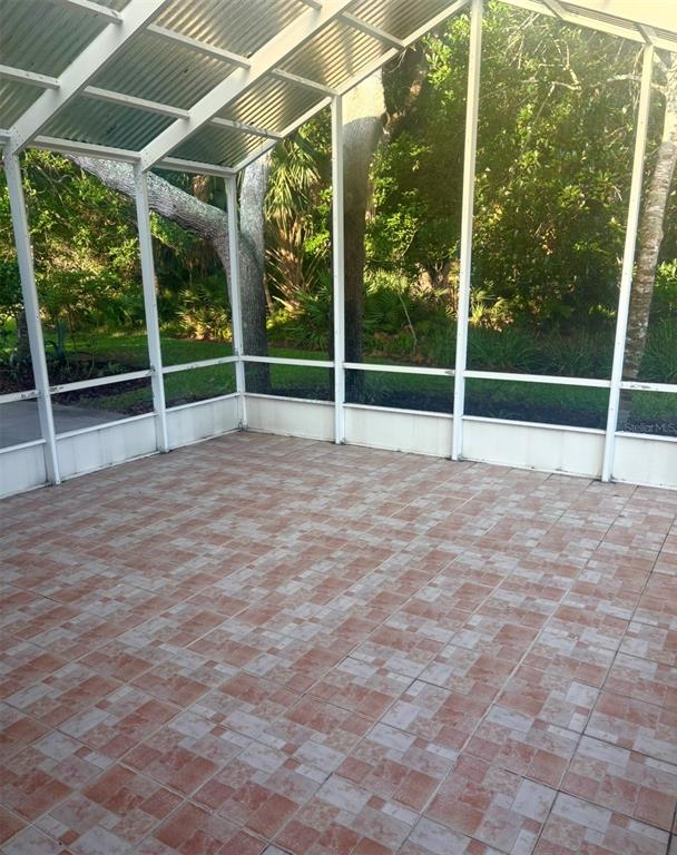 A screened-in porch with a metal roof and tiled flooring overlooks a wooded backyard — 3 SAN JOSE DRIVE, PALM COAST, FL