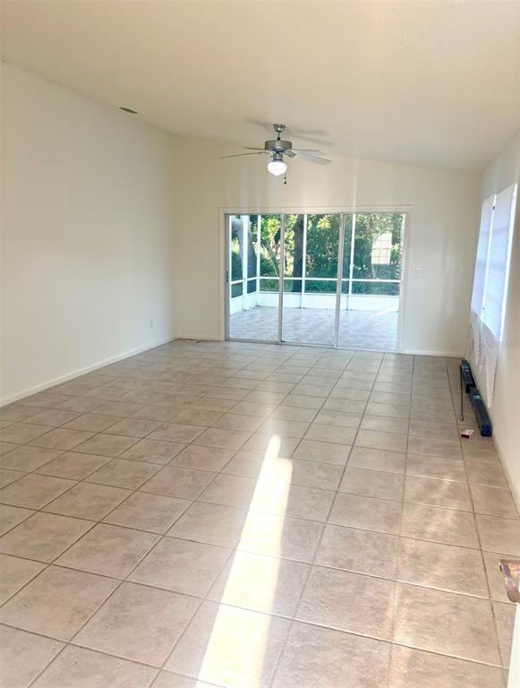An empty room with light-colored tile flooring, a ceiling fan, and sliding glass doors — 3 SAN JOSE DRIVE, PALM COAST, FL