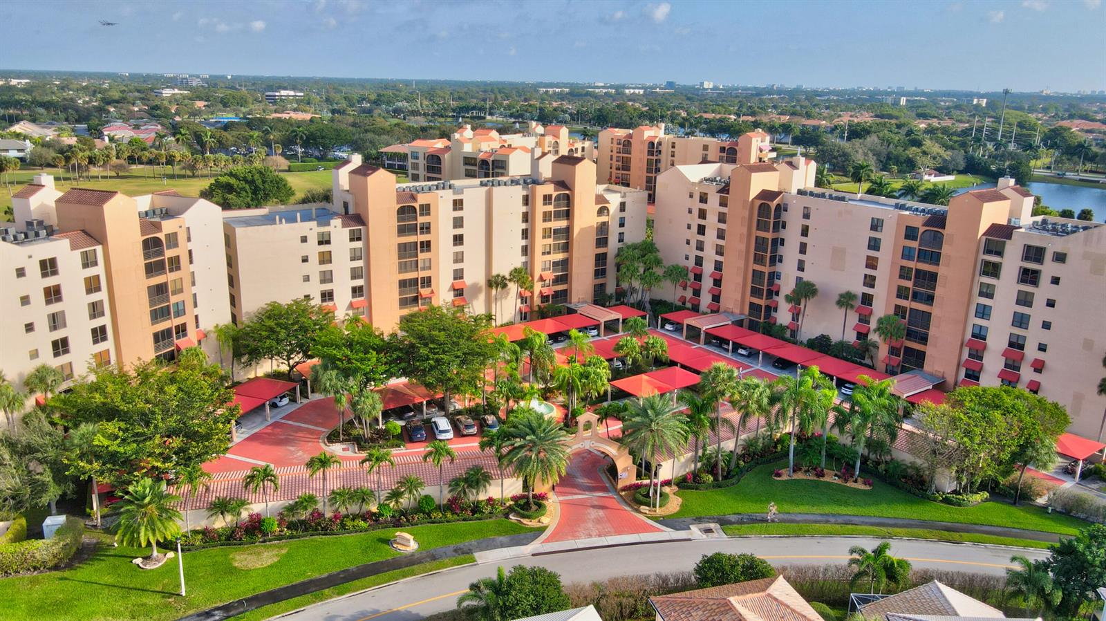 An aerial view of a multi-story apartment complex with covered parking and landscaped grounds — 7225 Promenade Drive # 102, Boca Raton FL 33433, BOCA RATON, FL