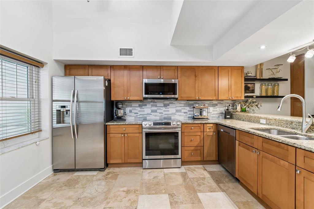 A kitchen with wood cabinets, stainless steel appliances, granite countertops, and a tile floor — 2599 DOLLY BAY DRIVE UNIT 302, PALM HARBOR, FL