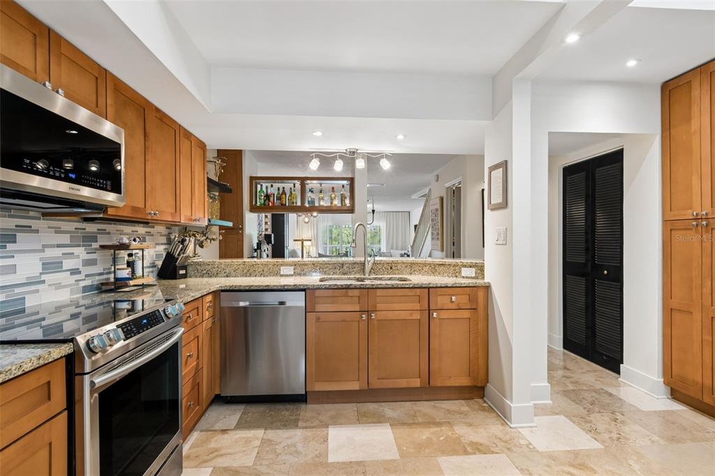 A kitchen features wood cabinets, granite countertops, stainless steel appliances, and a tiled floor — 2599 DOLLY BAY DRIVE UNIT 302, PALM HARBOR, FL