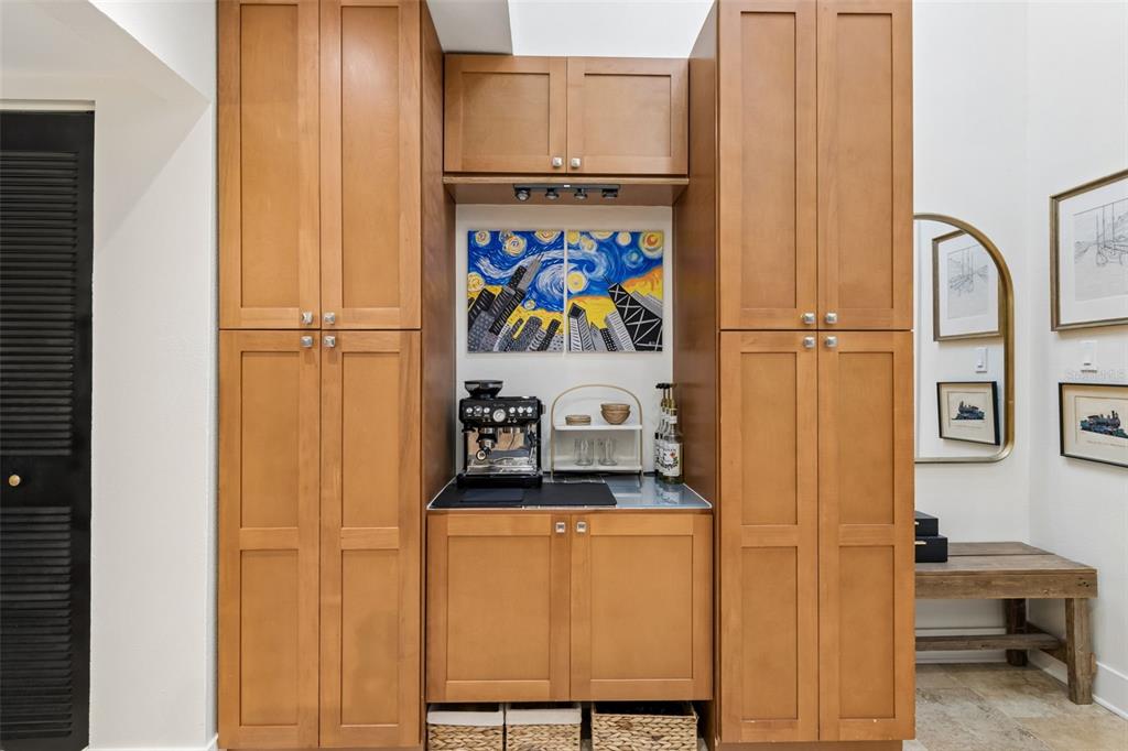 A built-in wooden coffee bar features cabinetry, a countertop, and artwork in a home interior — 2599 DOLLY BAY DRIVE UNIT 302, PALM HARBOR, FL