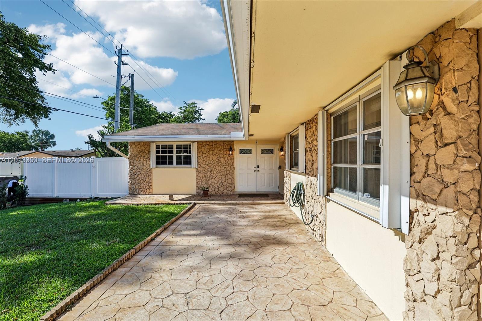 A stone-accented house exterior features a covered patio, double front doors, and a lawn — 108 SE 4th Ter, Dania Beach FL 33004, DANIA BEACH, FL