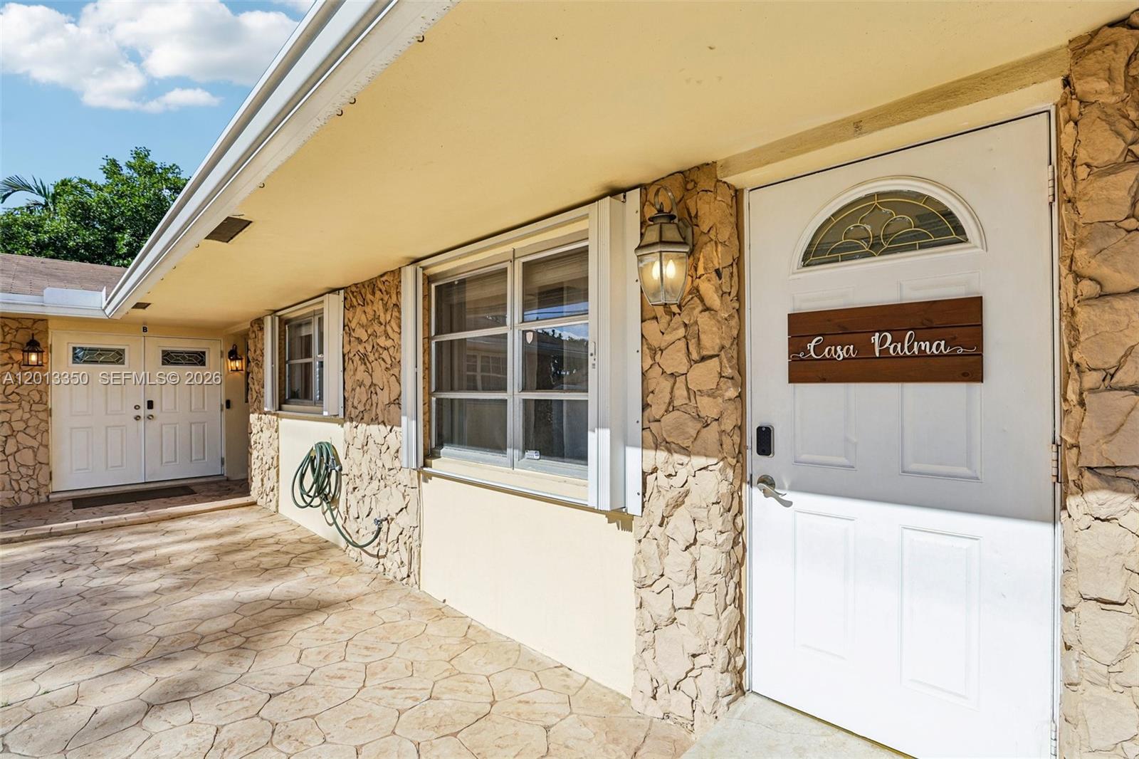 A stone-clad exterior wall features a white door with a Casa Palma wooden sign — 108 SE 4th Ter, Dania Beach FL 33004, DANIA BEACH, FL