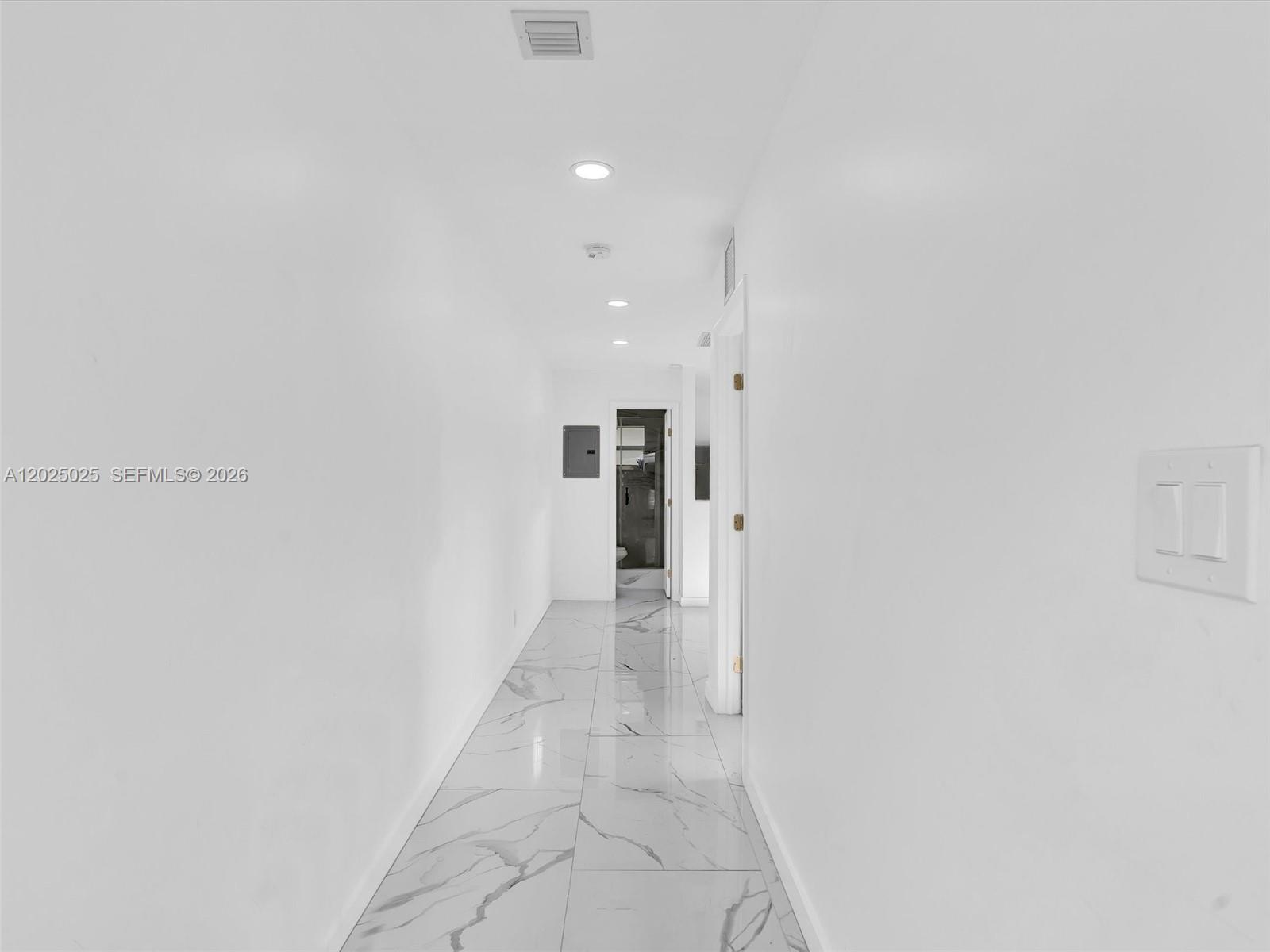 A bright hallway features white walls, recessed lighting, and white marble-patterned tile flooring — HOLLYWOOD, FL