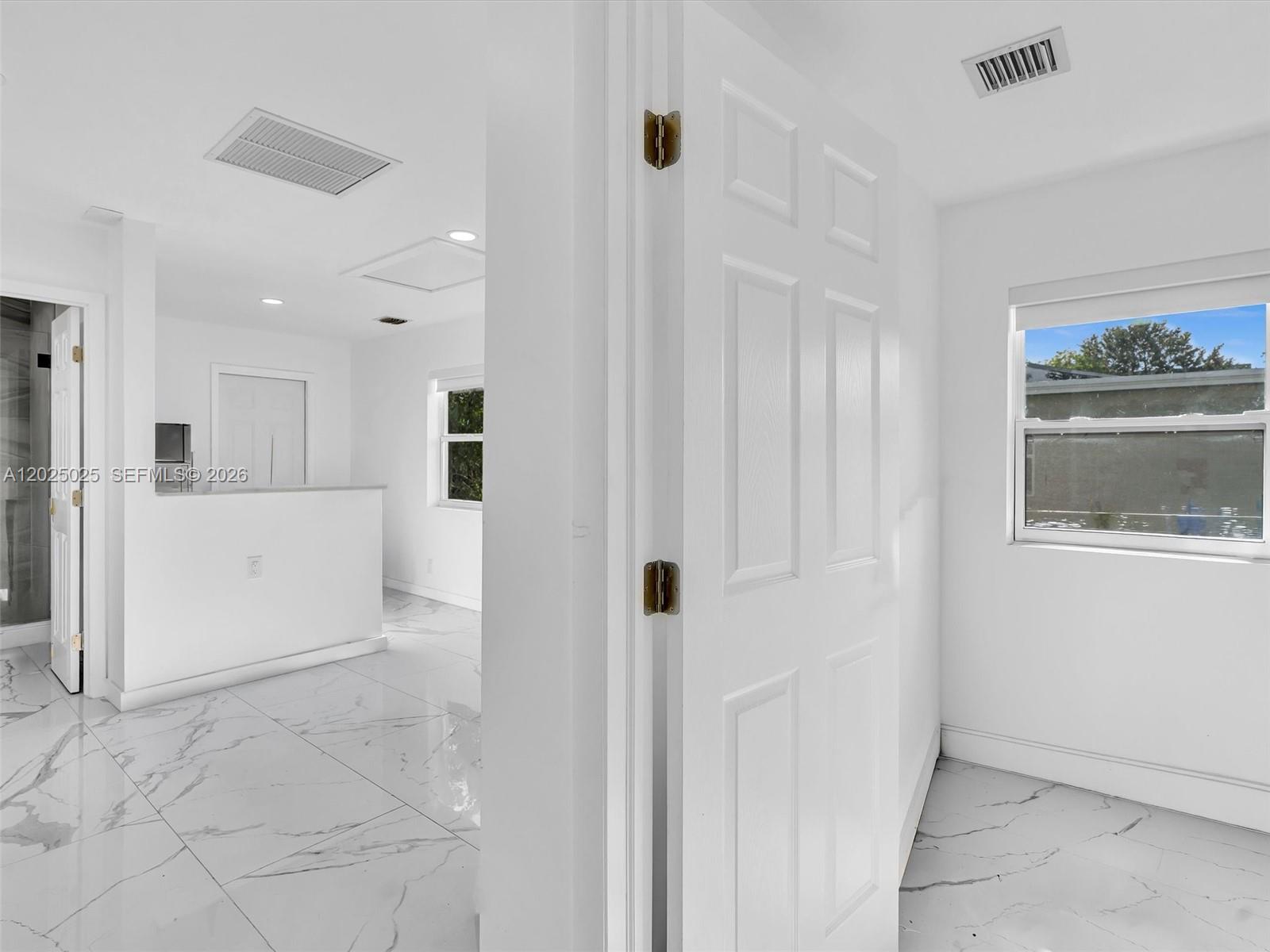 A white interior room features marble-patterned tile flooring and a doorway leading to another space — HOLLYWOOD, FL