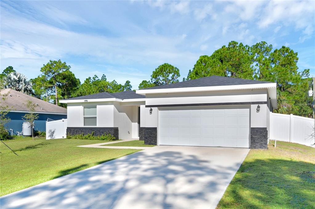 A single-story house with a white exterior, black stone accents, and a two-car garage — 643 FLYNN STREET SE, PALM BAY, FL