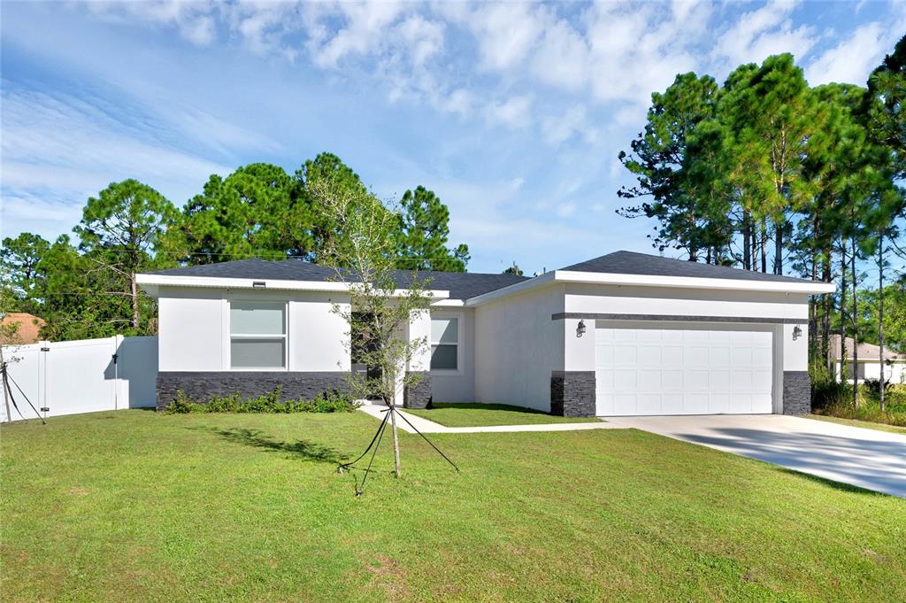 A single-story house with white stucco walls, dark stone accents, and a two-car garage — 643 FLYNN STREET SE, PALM BAY, FL