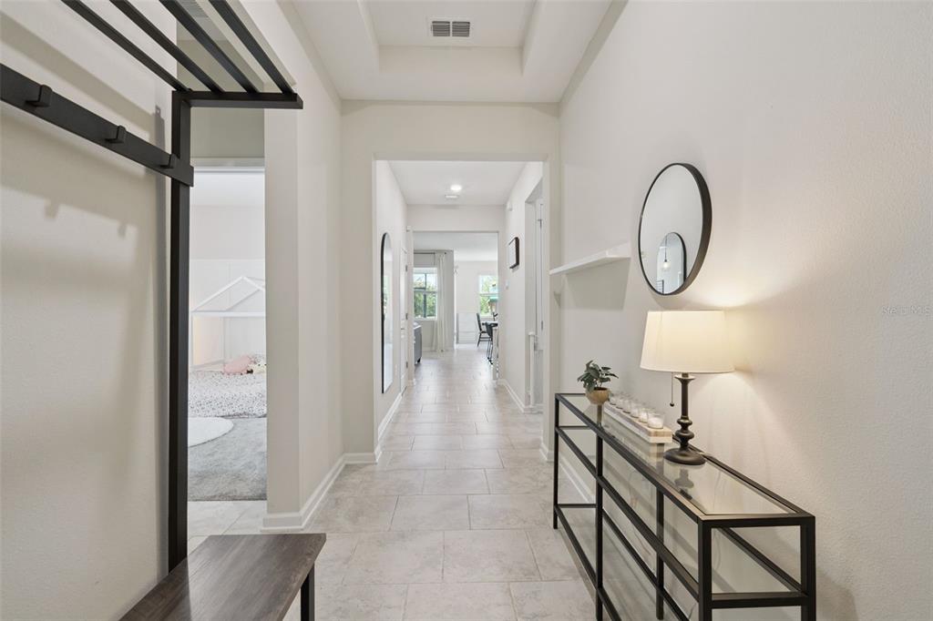 A bright hallway features light tile flooring, a glass console table, and a coat rack — 897 CARMILLION COURT, GROVELAND, FL