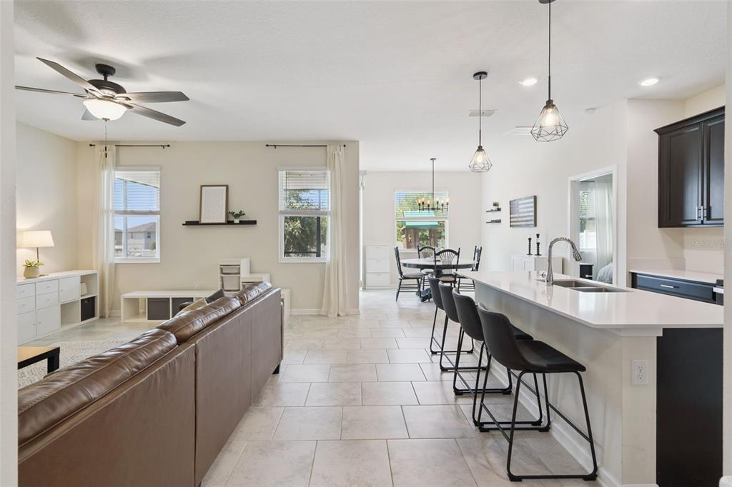An open-concept living room and kitchen featuring tile floors, dark cabinetry, and a breakfast bar — 897 CARMILLION COURT, GROVELAND, FL